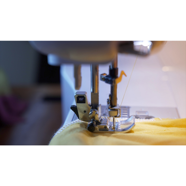 Needle of a sewing machine with yellow fabric underneath